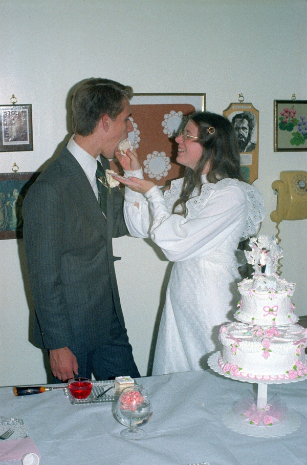 Don and Lois Colton at their wedding reception, Lois feeds cake to Don, 1975