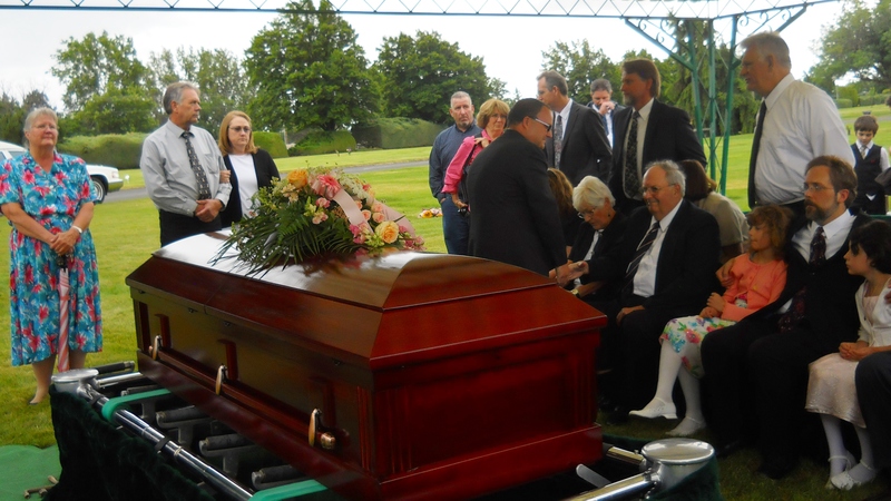 Crowd: Casket, Inge, Herm, Evee, Eric, Becca. Standing: xx, April, Steve, James, Perry, Don. Graveside at Einan's